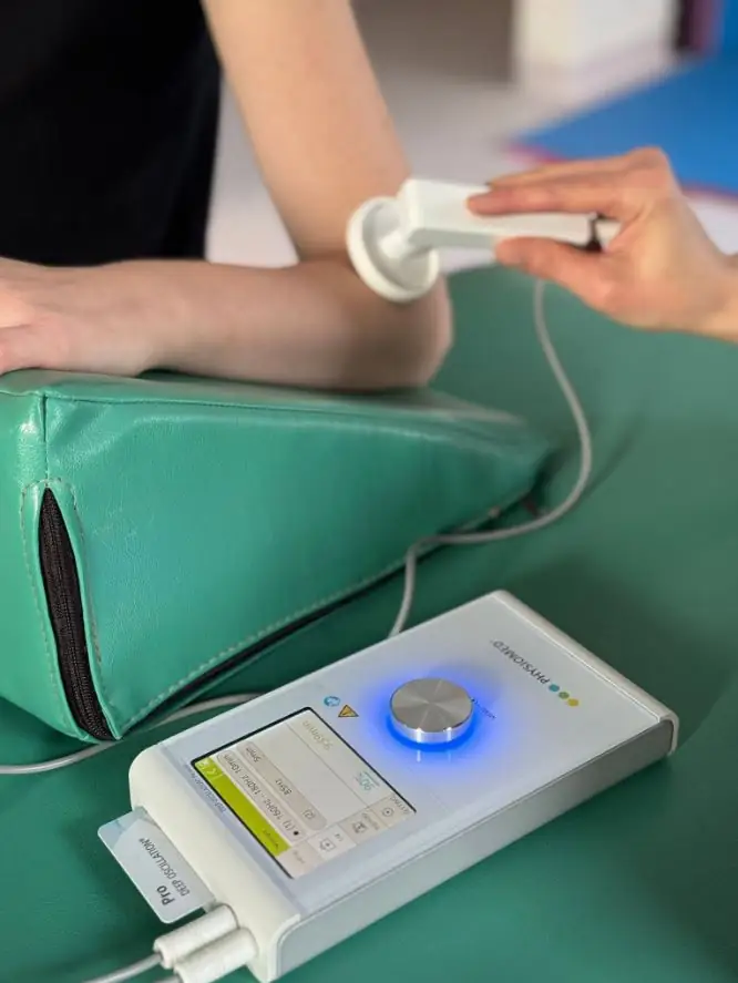 Aplicare de terapie Deep Oscillation la cot, cu aplicatorul manual și aparatul Physiomed pe masă – Clinica Kinetoterapia Piatra-Neamț