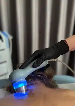 Terapie cu ultrasunete: sonda cu lumină albastră aplicată pe spate – Clinica Kinetoterapia Piatra-Neamț