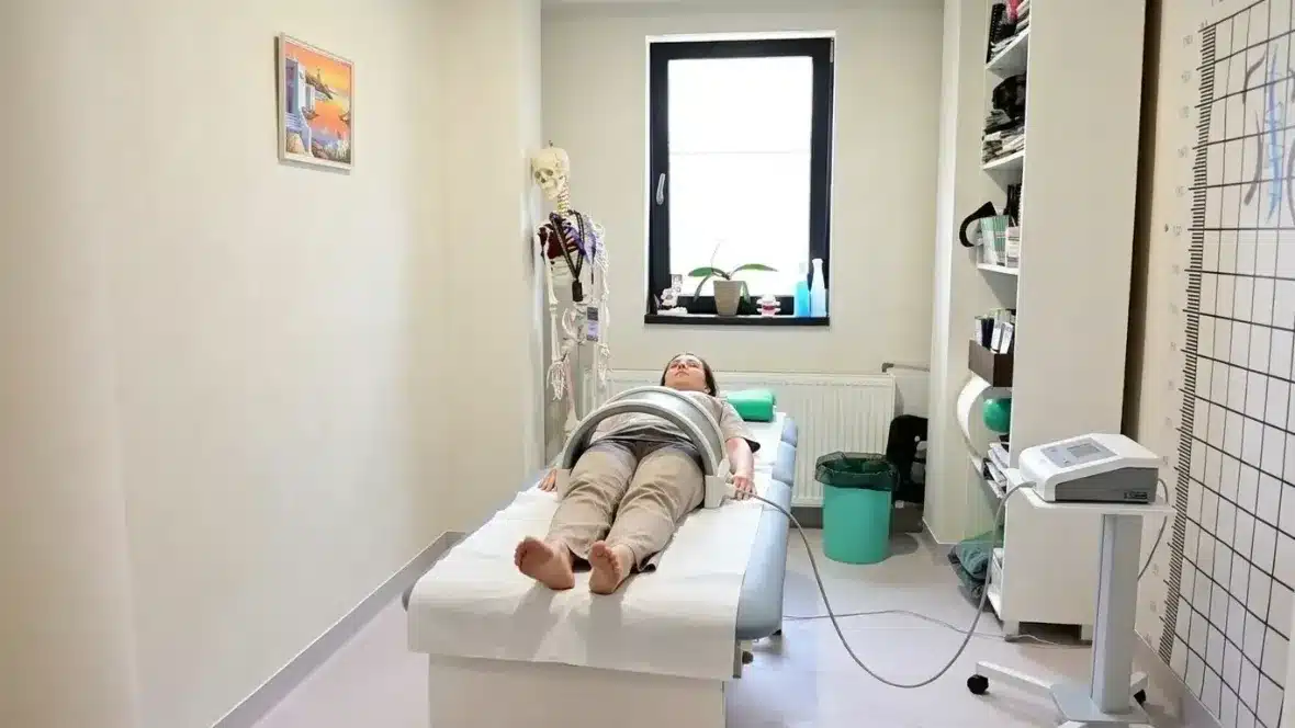 Magnetoterapie: pacientă întinsă pe masă, cu solenoidul aparatului poziționat peste zona șoldurilor – Clinica Kinetoterapia Piatra-Neamț