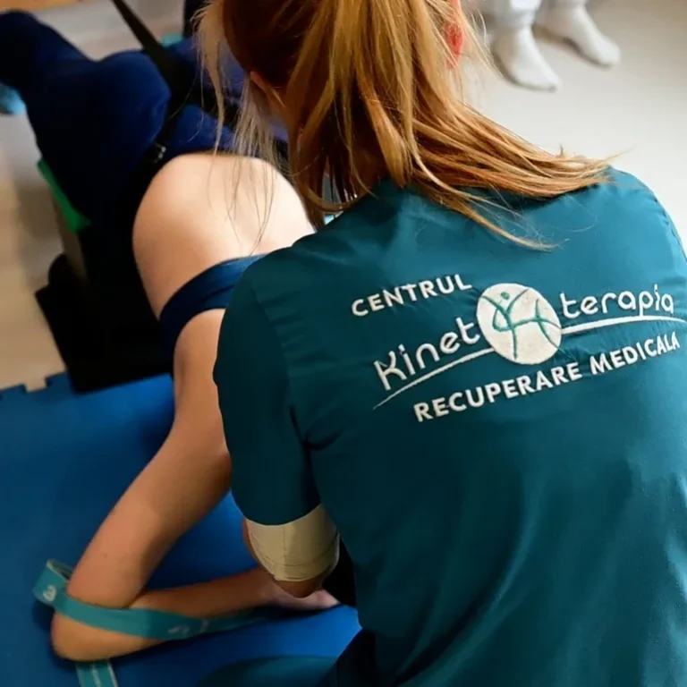 Kinetoterapeut asistând un pacient la exerciții de recuperare cu bandă elastică